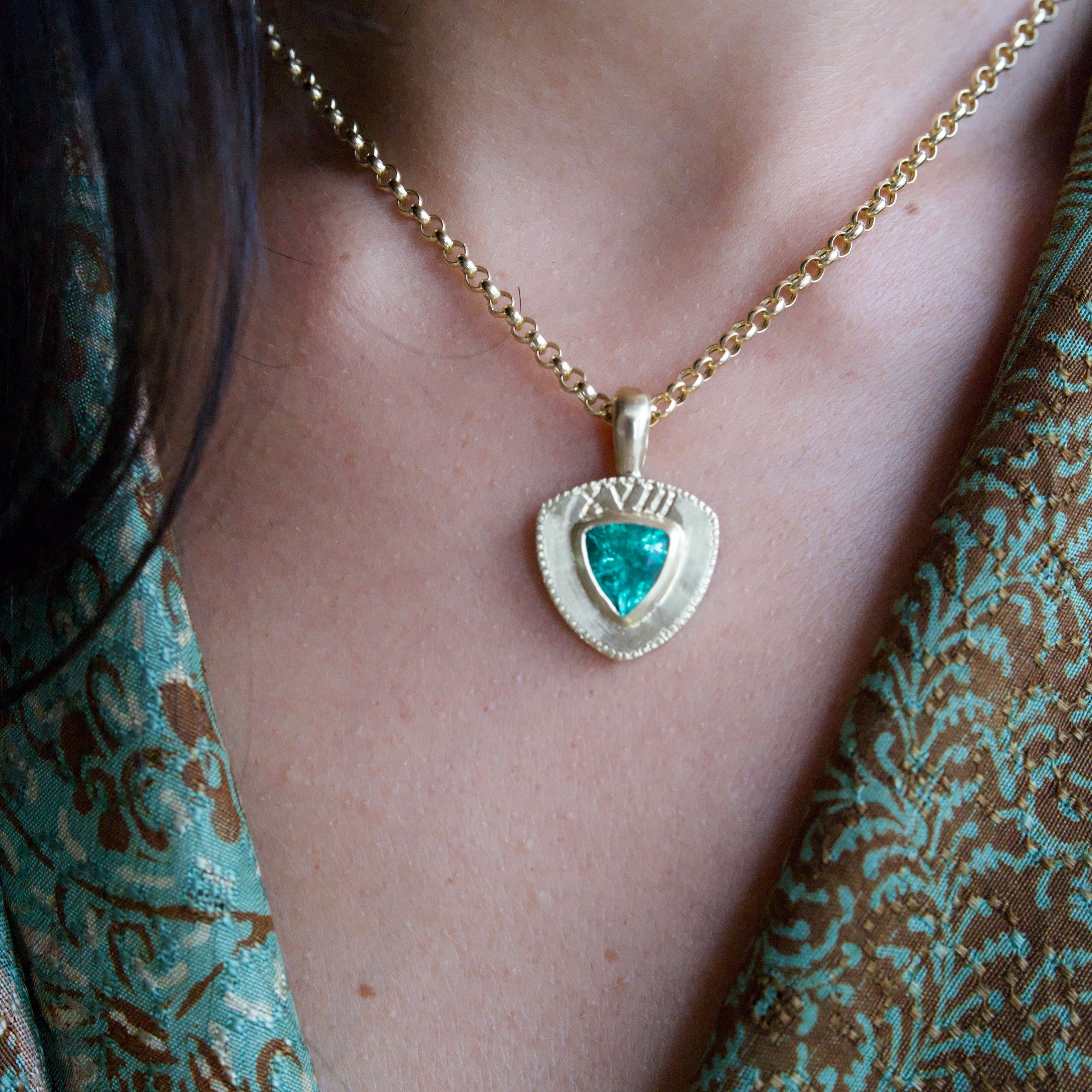 Trillion Cut Zambian Emerald Necklace in 18k Gold against Skin